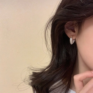 Elegant white heart-shaped earrings with gold trim worn by a model in warm light