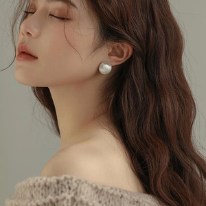Minimalist large matte white pearl stud earrings on model for a sophisticated autumn look