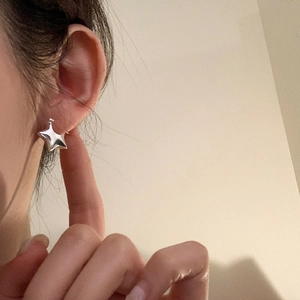 Pendientes de aro en forma de estrella 3D plateada pulida usados por una modelo minimalista