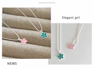 Dettaglio dei ciondoli a fiore in smalto rosa e verde su catenine a sfere d'argento