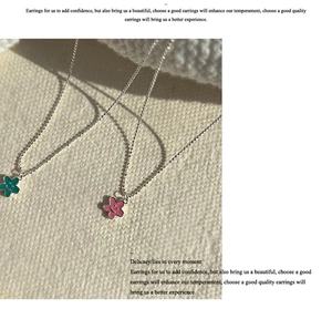 Dettaglio di ciondoli a fiore con sorriso rosa e ciano su catenine a sfere d'argento