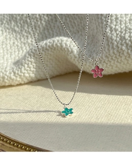 Dettaglio dei ciondoli a fiore con sorriso rosa e verdi su catene a sfere in argento