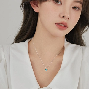 Collana a stella con fiore sorridente e ciondolo blu su modella con camicia bianca