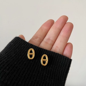 Detalle macro de pendientes ovalados huecos en oro brillante sujetos a mano
