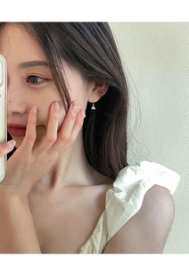Close-up of elegant lily of the valley bell-shaped earrings worn by a model in gold