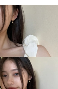 Close-up of elegant gold lily of the valley earrings worn on a model with warm lighting