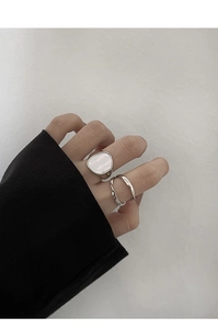 Detalle de anillo plateado trenzado con incrustación de nácar blanco irregular