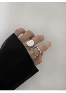 Detalle de anillos S925 de plata trenzados con incrustación de concha en la mano