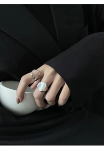 Detalle de anillo de plata de doble capa y anillo con concha grande en la mano
