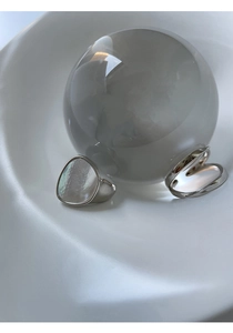 Detalle de anillos plateados con incrustación de nácar y líneas retorcidas minimalistas