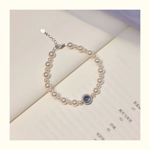 Detailed macro view of S925 silver clasp and heart charm on pearl bracelet with blue gem
