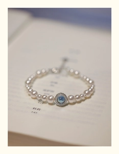 Macro shot of pearl bracelet featuring a blue gemstone center with zircon accents