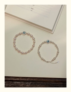 Detail of pearl bracelets featuring round aquamarine charms and zircon accents on a warm background