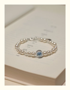 Detailed close-up of a pearl bracelet featuring a blue gemstone pendant on a book