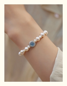 Detail of a pearl bracelet featuring a blue gemstone pendant with zircon micro-paving