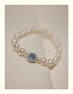 Macro shot of pearl bracelet featuring a blue gemstone pendant with zircon pavé setting