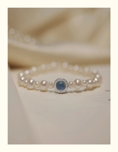 Detail shot of elegant pearl bracelet with blue round gemstone pendant and pavé zircon