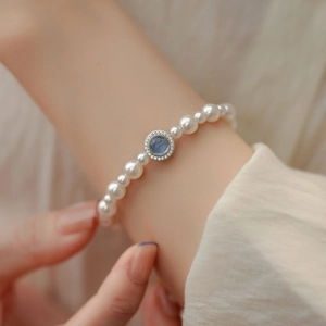 Elegant pearl bracelet with a round blue zircon centerpiece and sparkling halo on wrist