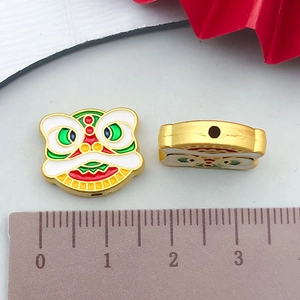 Detail showing two colorful enamel Chinese lion dance pendants with dimensions on scale