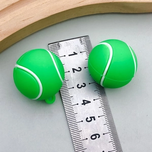 Macro detail of two green tennis ball pendants with small loop ring and scale reference