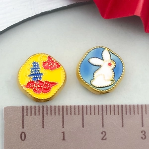 Detail shot of Chinese style enamel pendants with rabbit and pagoda designs measuring 12mm
