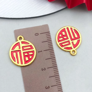 Macro detail of red enamel Fu character pendant charm with ruler showing 2cm diameter