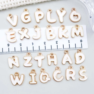 White enamel gold-plated alloy alphabet pendants set with size scale for DIY jewelry