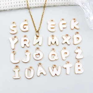 Detail of white enamel gold-plated alphabet letter charms for DIY necklaces