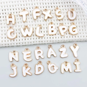Detail of white enamel and gold alloy alphabet letter pendants for DIY jewelry