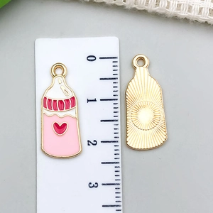 Detalle de los colgantes de biberón rosa con regla para referencia de talla 27mm