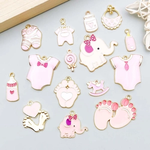 Detalle de colgantes de bebé en esmalte rosa y dorado para bisutería artesanal