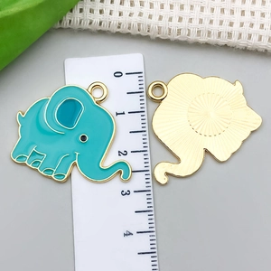Vista detallada de colgante de elefante esmaltado azul con reverso dorado y aro de metal