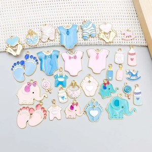 Detalle de dijes esmaltados de bebé con biberones y elefantes para joyería artesanal