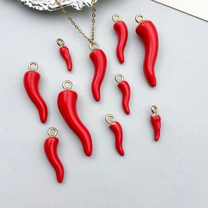 Vue détaillée de breloques piment en émail rouge avec boucles dorées pour bijoux