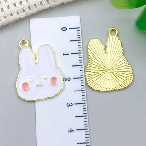 Detailed view of pink and white enamel bunny pendants with size measurement tool