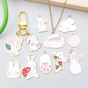 Detailed view of pink and white enamel bunny charms on gold-plated necklaces and keychains