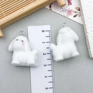 Macro detail of a 2.5cm flocked white dog pendant with silver ring for DIY jewelry making