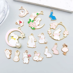 Detail of assorted white and pink enamel rabbit charms with gold plating for DIY jewelry