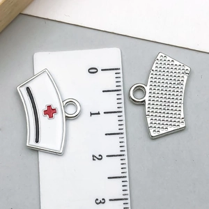 Detail of 1.5cm white enamel nurse hat charm with red cross and textured silver back