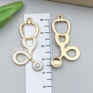 Détails recto-verso de pendentifs stéthoscope dorés avec émail blanc et strass pour DIY