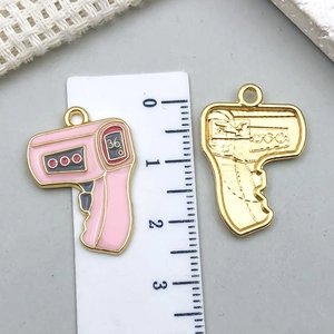 Detailed macro view of front and back thermometer charms with ruler for size reference