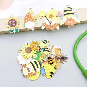 Detailopname van geel emaille bij en zonnebloem bedeltjes voor DIY-sieraden maken