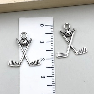 Detailed size view of silver golf club and ball charms with a ruler measurement