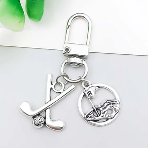 Detail of silver golf themed keychain with clubs and green landscape pendant charm