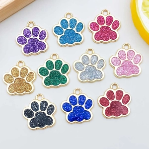 Dettaglio di dieci ciondoli a forma di zampa smaltati con glitter per creazione gioielli DIY