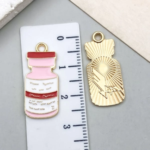 Detail of pink enamel medicine bottle charms showing front design and engraved sun pattern back