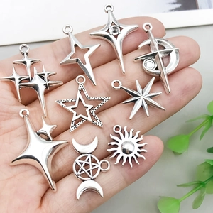 Antique silver star and moon celestial charms held in hand for DIY jewelry making