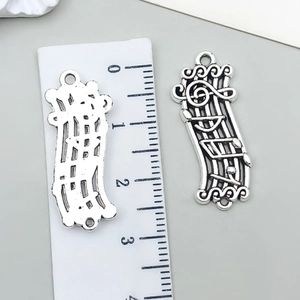 Makrofoto eines 3,5 cm großen Vintage-Silber-Musiknoten-Anhängers mit Play-Text-Details