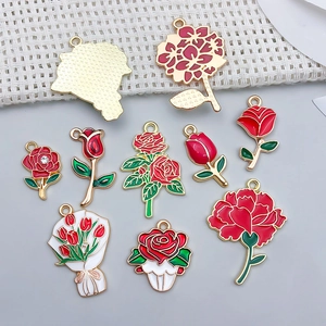 Macro detail of various red floral charms including roses and tulips with gold plating