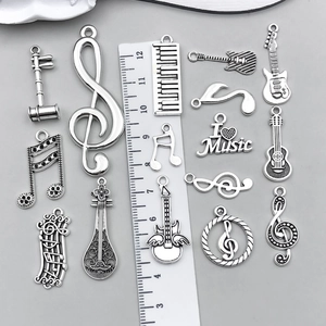 Antike Silber-Musikanhänger mit Gitarre und Noten, zusammen mit einem Lineal abgebildet